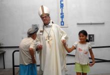 Argentine Cardinal Jorge Mario Bergoglio, elected March 13, 2013 as Pope Francis, holds the hands of a woman and girl during Holy Thursday Mass in 2008 at a church in a poor section of Buenos Aires, Argentina. (CNS/Reuters/Enrique Garcia Medina)