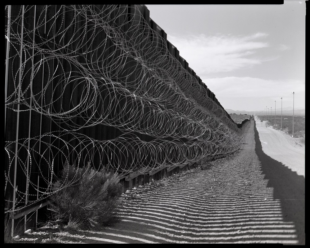 The border wall in Douglas, Arizona, in October 2020. The barbed wire is a typical feature on parts of the wall that border two cities, such as this one straddling Douglas and Agua Prieta, Mexico. (© Lisa Elmaleh) The border wall in Douglas, Arizona, in October 2020. The barbed wire is a typical feature on parts of the wall that border two cities, such as this one straddling Douglas and Agua Prieta, Mexico. (© Lisa Elmaleh)