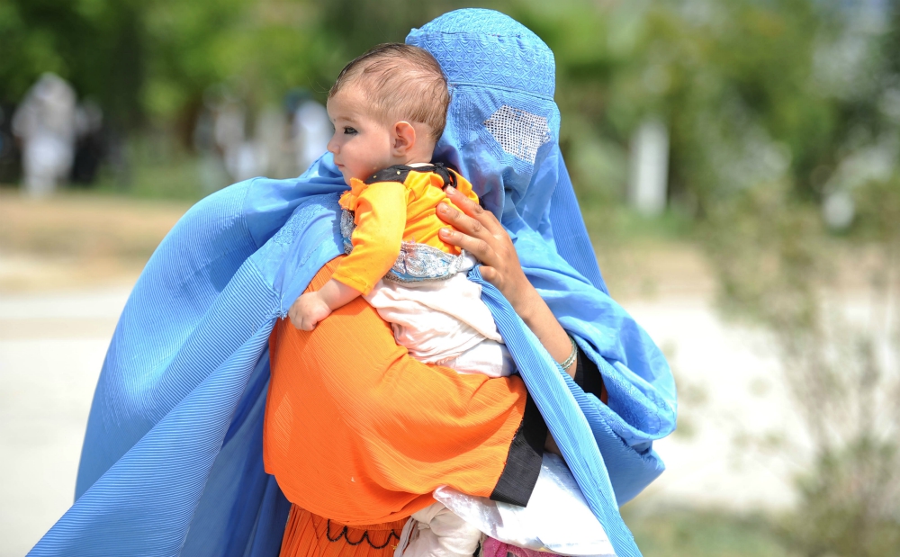 A displaced Afghan woman arrives with her child July 16, 2016, at a U.N. High Commissioner for Refugees camp upon their voluntary return to Afghanistan's Nangarhar Province from neighboring Pakistan. (CNS/Reuters/Ghulamullah Habibi) A displaced Afghan woman arrives with her child July 16, 2016, at a U.N. High Commissioner for Refugees camp upon their voluntary return to Afghanistan's Nangarhar Province from neighboring Pakistan. (CNS/Reuters/Ghulamullah Habibi)