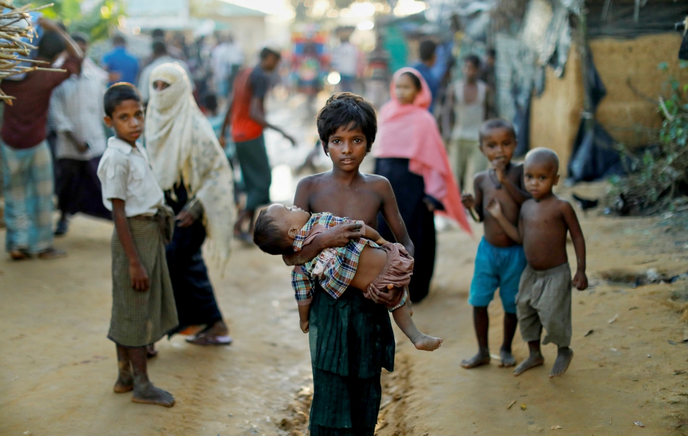 A young Rohingya refugee carries a child Oct. 10 while walking in a camp near Cox's Bazar, Bangladesh. (CNS/Reuters/Damir Sagolj) A young Rohingya refugee carries a child Oct. 10 while walking in a camp near Cox's Bazar, Bangladesh. (CNS/Reuters/Damir Sagolj)