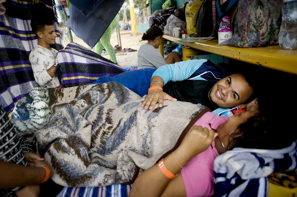 Tomas Torres puts his hand on the stomach of his pregnant wife, Elvia Perez de Torres, as they rest at a camp for migrants at a sports facility in Tijuana, Mexico. (CNS/David Maung) Tomas Torres puts his hand on the stomach of his pregnant wife, Elvia Perez de Torres, as they rest at a camp for migrants at a sports facility in Tijuana, Mexico. (CNS/David Maung)