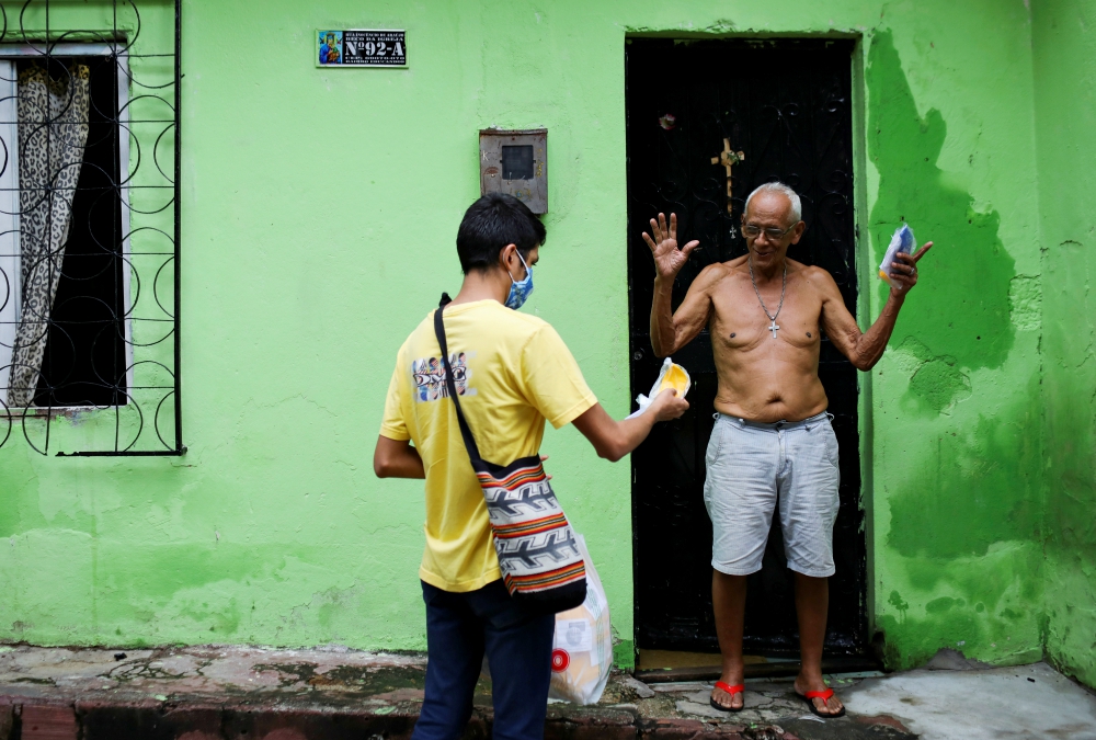 Seminarian Renan Alberto Lima de Oliveira, 21, assigned to Our Lady of Perpetual Help Catholic Church in Manaus, Brazil, delivers a protective mask to a resident in one of the city's slums May 21 to minimize the spread of COVID-19. (CNS/Reuters) Seminarian Renan Alberto Lima de Oliveira, 21, assigned to Our Lady of Perpetual Help Catholic Church in Manaus, Brazil, delivers a protective mask to a resident in one of the city's slums May 21 to minimize the spread of COVID-19. (CNS/Reuters)