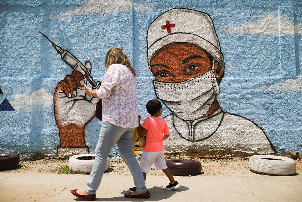 A woman and child walk past a painting on a wall in Rio de Janeiro A woman and child walk past a painting on a wall March 12 in Rio de Janeiro during the COVID-19 pandemic. (CNS/Reuters/Pilar Olivares)