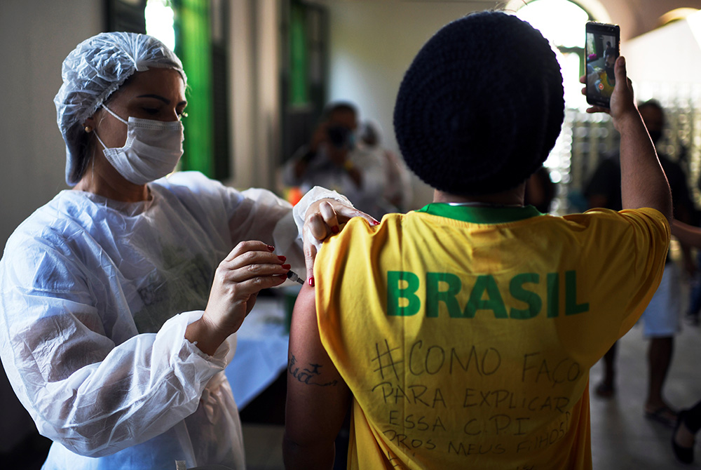 A health care worker administers a dose of the Johnson & Johnson COVID-19 vaccine to a resident taking a selfie in Rio de Janeiro on July 10. (CNS/Reuters/Lucas Landau) A health care worker administers a dose of the Johnson & Johnson COVID-19 vaccine to a resident taking a selfie in Rio de Janeiro on July 10. (CNS/Reuters/Lucas Landau)