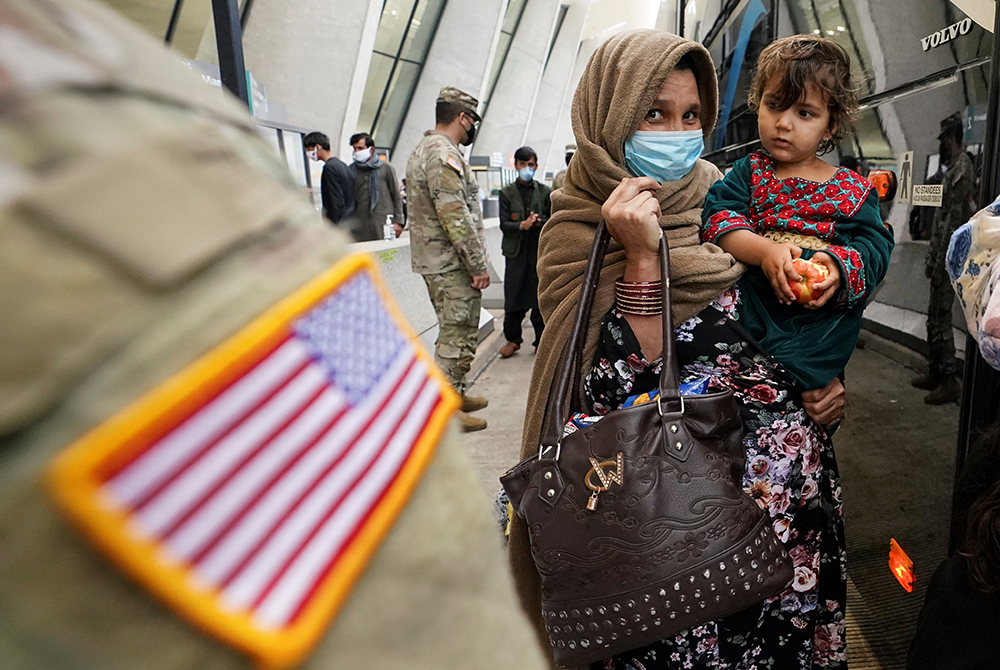 Upon their arrival, Afghan refugees board a bus at Dulles International Airport Sept. 1 in Dulles, Virginia, taking them to a processing center. (CNS/Reuters/Kevin Lamarque)