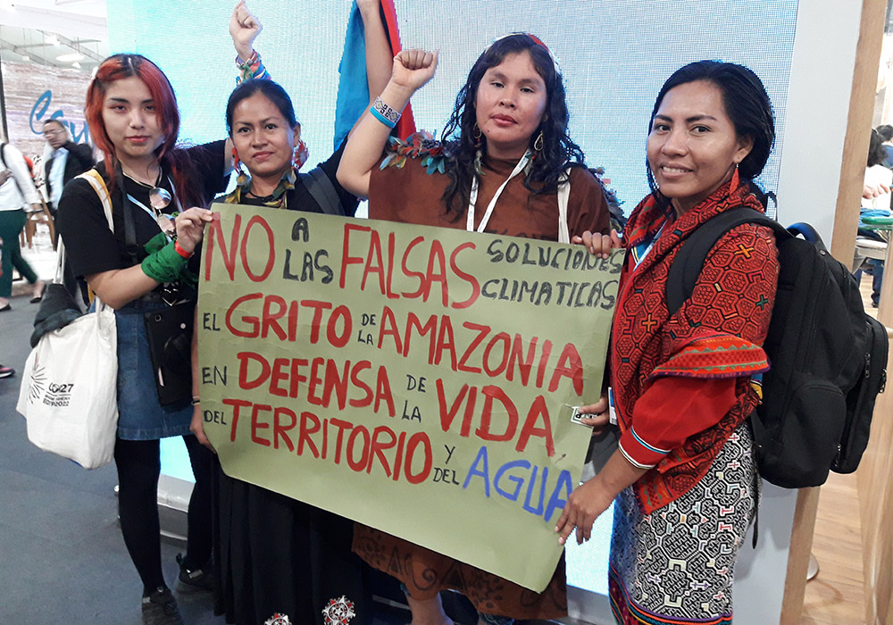 At COP27 in Sharm el-Sheikh, Egypt, a group of young people from Peru with a protest sign, demanding: "No false climate solutions, the Amazon cries out in defense of life, land and water." (Courtesy of Ana María Siufi)
