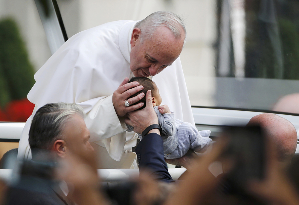 Pope Francis stops to kiss a child as he makes his way in the popemobile to Independence Hall Sept. 26, 2015, in Philadelphia. (CNS/Reuters/Jim Bourg)