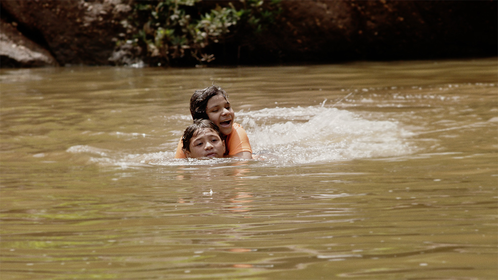 La adolescente hondureña María nada con su hermano en la película documental With This Light. (Foto: cortesía de Miraflores Films)