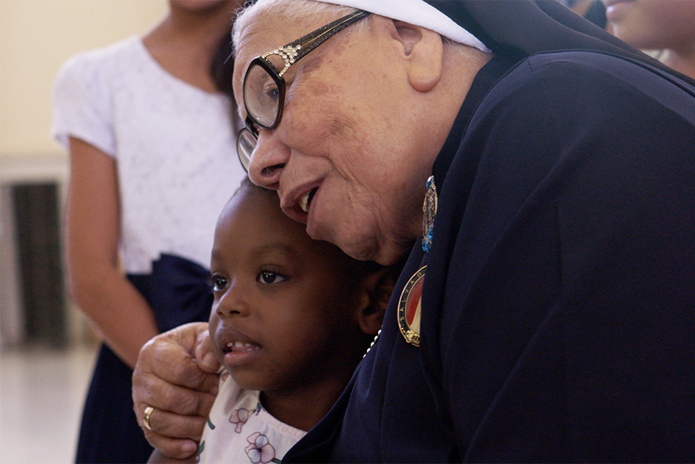 La Hna. María Rosa Legoll, de las Hermanas Escolares de San Francisco, abraza a un niño en el documental With This Light. (Foto: cortesía de Miraflores Films)