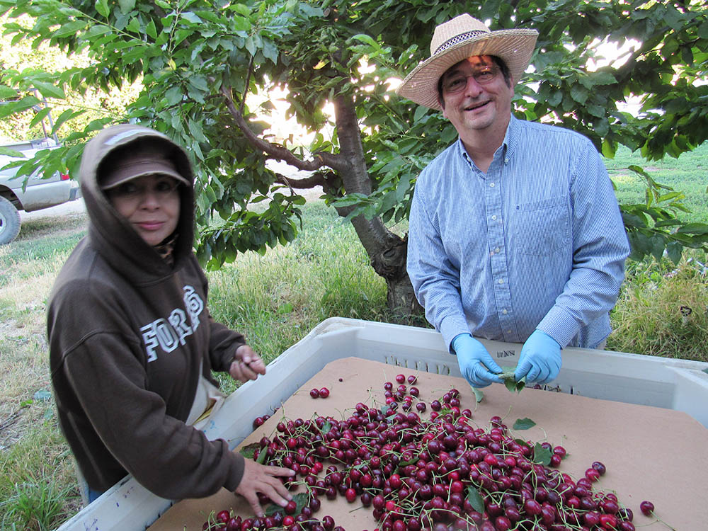 Bishop Joseph Tyson, right, meets with migrant farmworkers at a farm in Prosser, Washington, during the cherry harvest, Aug. 2, 2017. (Diocese of Yakima/Edgar Quiroga)