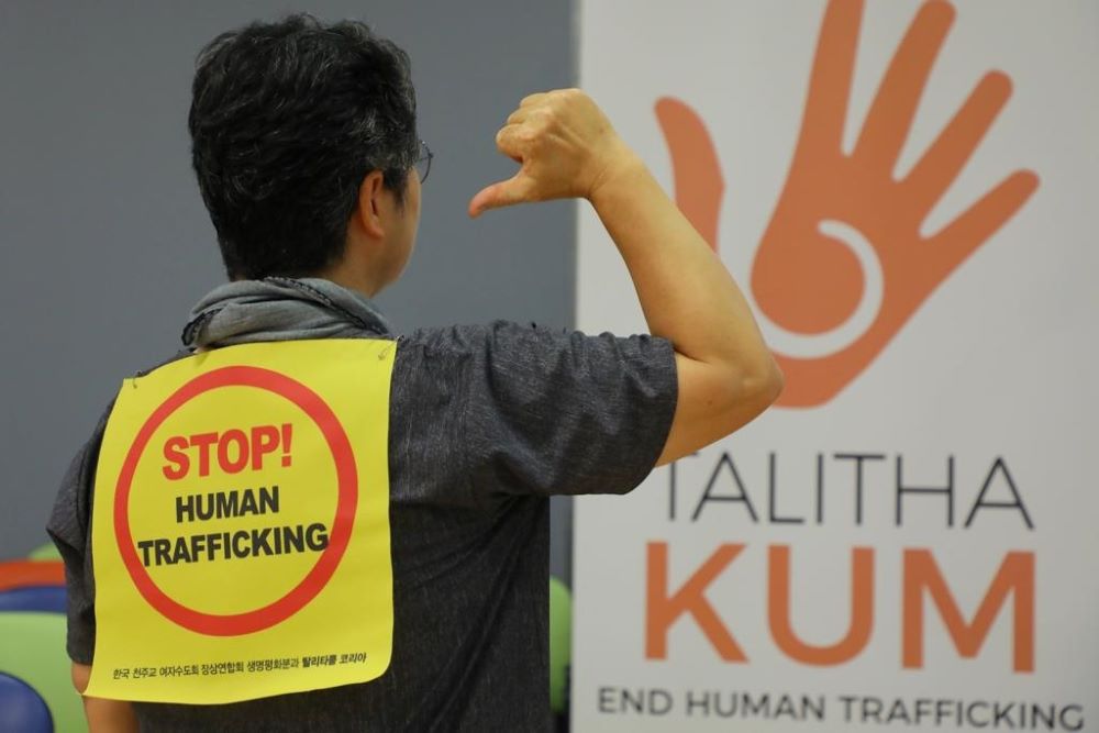An attendee points to a sign as women religious from around the world gather in Rome in 2019 to celebrate the 10th anniversary of Talitha Kum, an international network of religious women fighting human trafficking. (CNS/Courtesy of International Union of Superiors General)