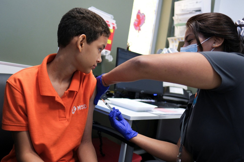Dengue fever, Archbishop of San Juan, Puerto Rico epidemic Young boy receives vaccine in arm from nurse