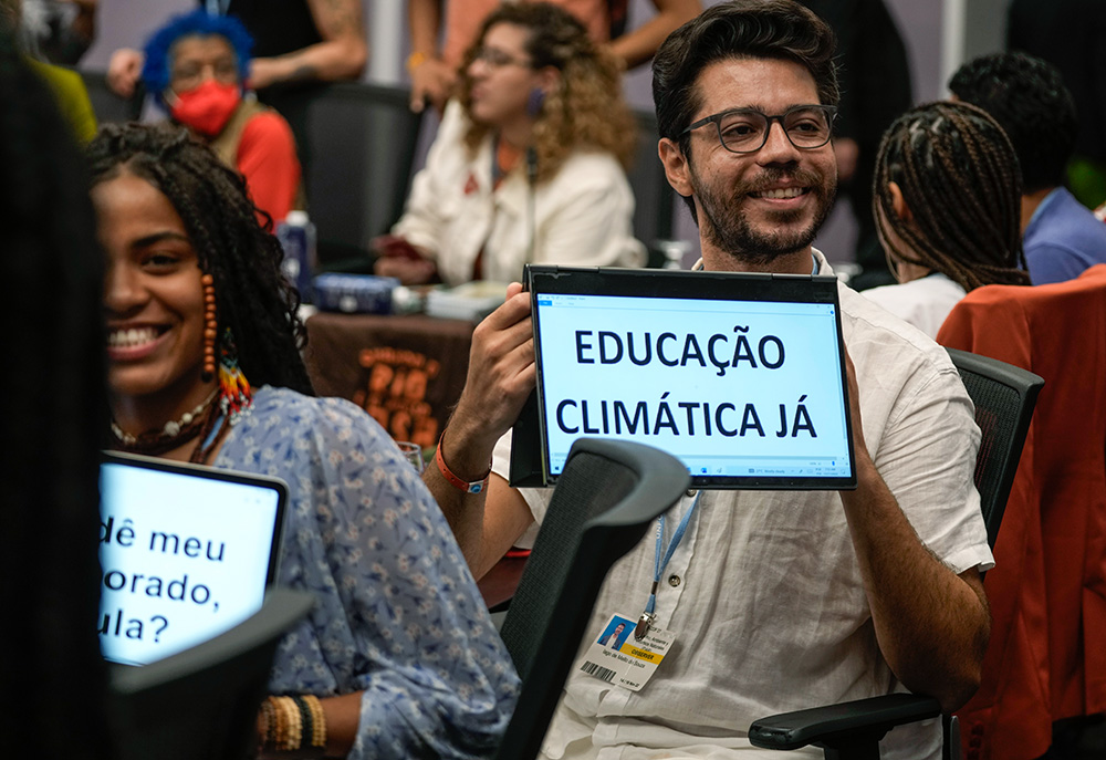 A man displays a sign in Portuguese that reads, "Climate education now," on Nov. 17, 2022, at the COP27 U.N. Climate Summit in Sharm el-Sheikh, Egypt. (AP/Peter Dejong)