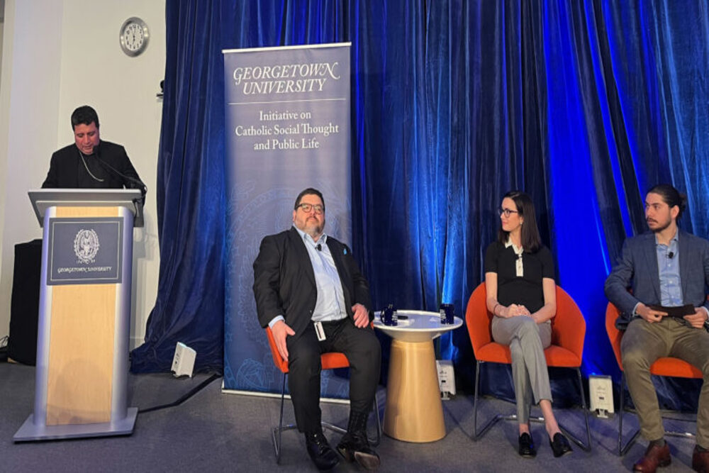 Georgetown Latino Leader Gathering, 2024 Three members seated, and one standing at lectern in front of blue backdrop
