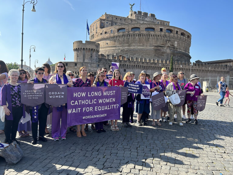 Women's Ordination, Pope Francis 60 Minutes interview. Women hold banners, in background is the Castel Sant'Angelo