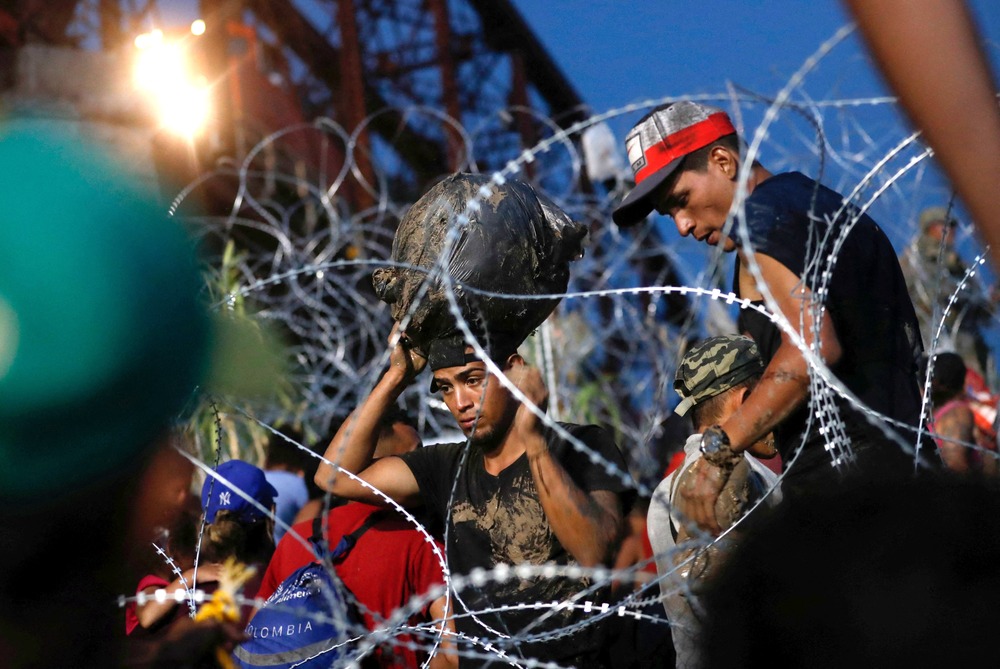 Executive Order, Biden, June 4, Immigration Young men framed by coils of barbed fencing.