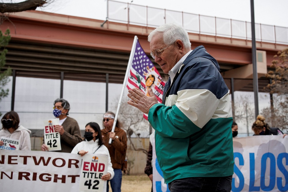 Ruben Garcia Garcia folds hand in prayer, supporters bearing banners seen in background