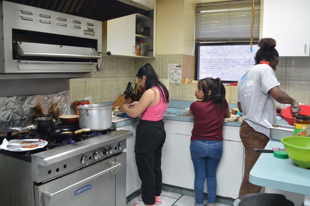 Young women from Latin America and Africa work in the kitchen during after-school hours at Bethany House of Hospitality for 18- to 25-year-old refugee women May 7. Young women from Latin America and Africa work in the kitchen during after-school hours at Bethany House of Hospitality for 18- to 25-year-old refugee women May 7.