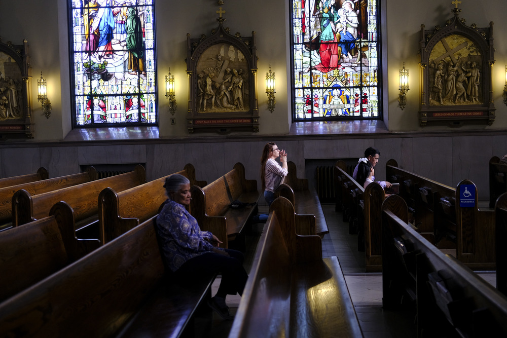 St. Peter the Apostle Catholic Church, Reading, Pennsylvania, 2024. Stained glass windows, stations of the cross, and people kneeling.