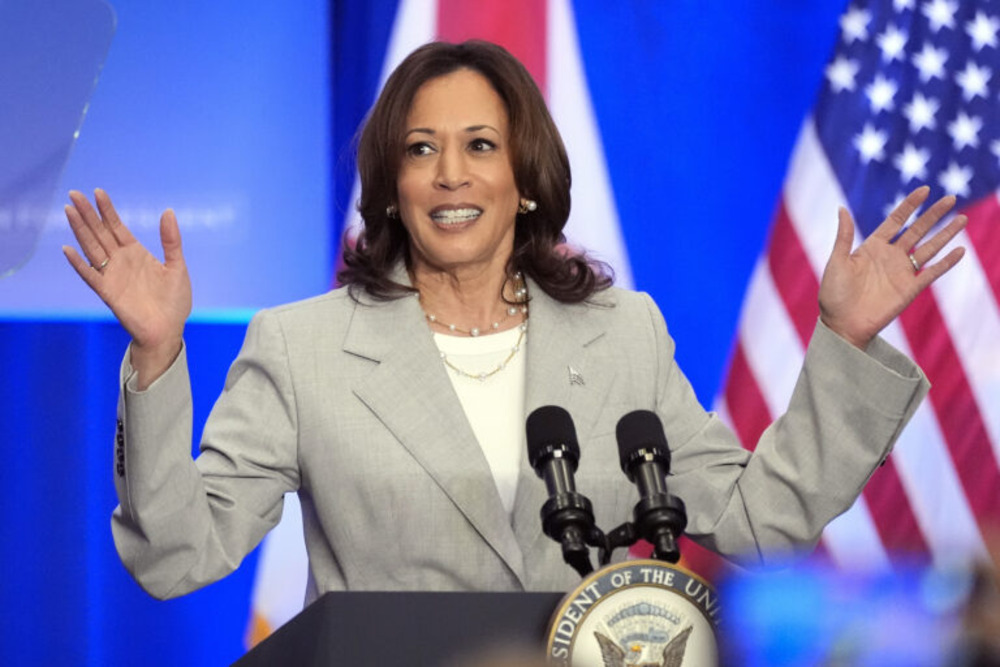 Vice President Kamala Harris, 2024. Harris raises hands, smiling, as she speaks at a lectern.