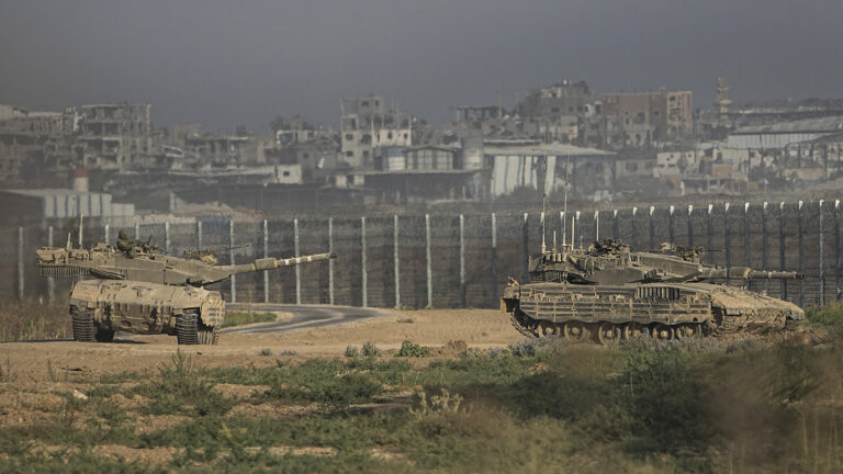 Israel-Gaza border, 2024. Tanks seen in foreground, border wall seen in background.