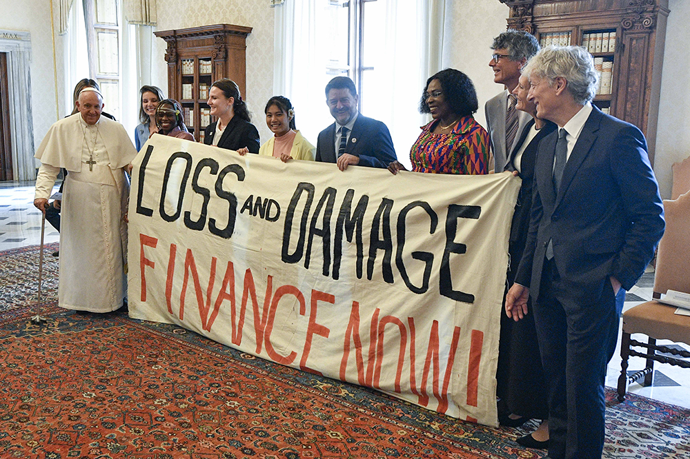 Pope Francis joins others in holding a banner during an audience at the Vatican June 5, 2023, with the organizers of the Green & Blue Festival. The banner calls for financing a "loss and damage" fund that was agreed upon at the COP27 U.N. climate conference in 2022. (CNS/Vatican Media)