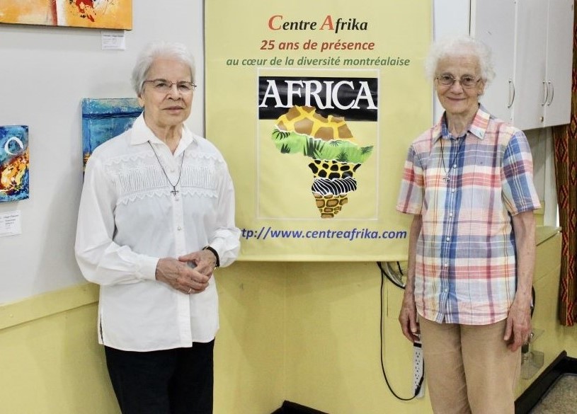 Las hermanas Monique Bonnefoy, a la izquierda, y Rita Toutant, de las Hermanas Misioneras de Nuestra Señora de África, junto a un cartel que en francés reza: "25 años en el corazón de la diversidad de Montreal", en el Centre Afrika. Las dos trabajaron muchos años en África y ahora ejercen su ministerio en el centro intercultural de Montreal, Canadá. (Foto: GSR/Joanna Kozakiewicz)
