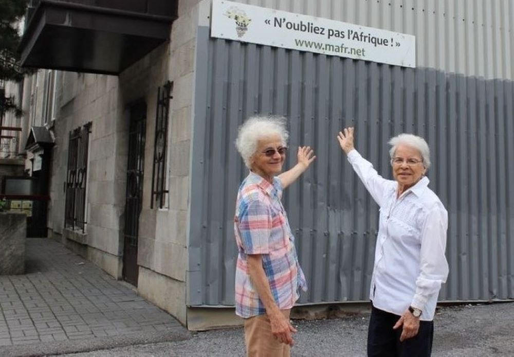 Las hermanas Rita Toutant, a la izquierda, y Monique Bonnefoy, de las Hermanas Misioneras de Nuestra Señora de África, señalan un cartel que reza: "No olviden a África", en el lateral de la casa misionera donde viven en Montreal. (Foto: GSR/Joanna Kozakiewicz)