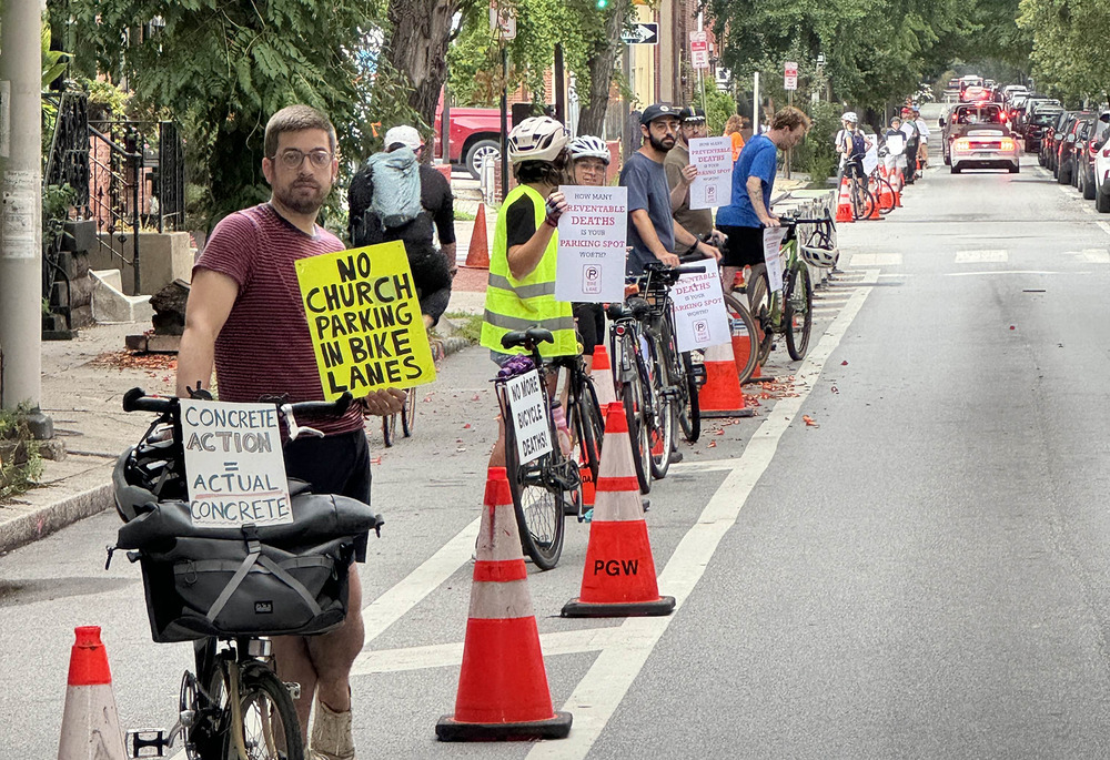 Philly Bike Action demonstration, Philadelphia. People with bikes and protest signs stand in a lane demarcated by traffic cones.