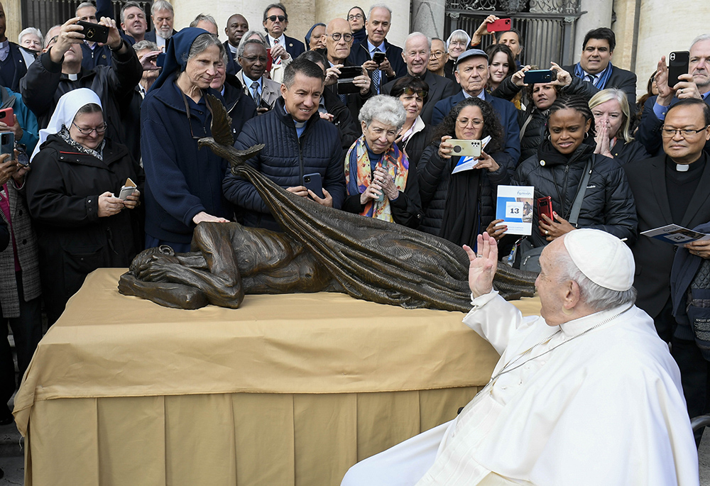 Pope Francis waves to members of the Vincentian religious orders and lay communities Nov. 9, 2022, after blessing Canadian artist Timothy Schmalz' sculpture "Sheltering." The statue, which features a dove laying a blanket over a homeless person, was to be used in conjunction with a Vincentian project to build homes for some 10,000 people in 160 countries. (CNS/Vatican Media)