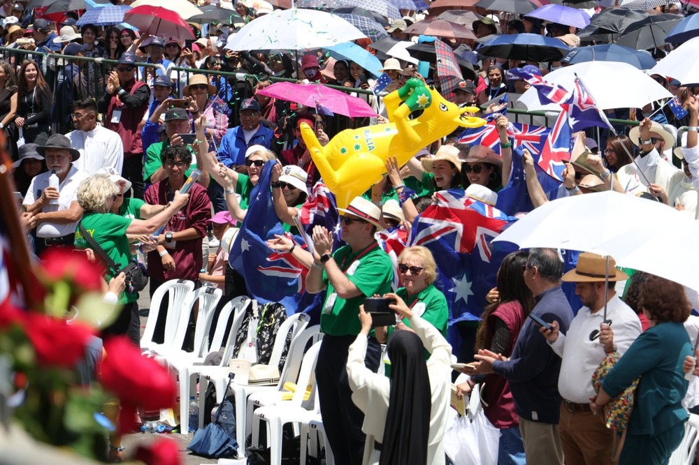Last day of 53rd International Eucharistic Congress, Sept. 15, 2024, Quito, Ecuador. Many people stand from plastic chairs cheering and waving flags etc.