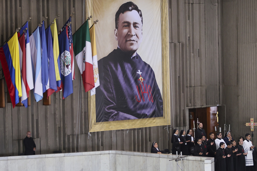 Rev. Moises Lira, beatification, Basilica of Our Lady of Guadalupe, Mexico City, Sept. 14, 2024. Large banner hangs on wall beside various flags.