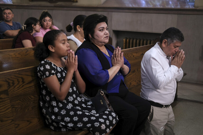 Parishioners of St. Peter the Apostle Catholic Church, Reading, Pa., June 9, 2024. Woman, man, and young girl pray in front pew of church.