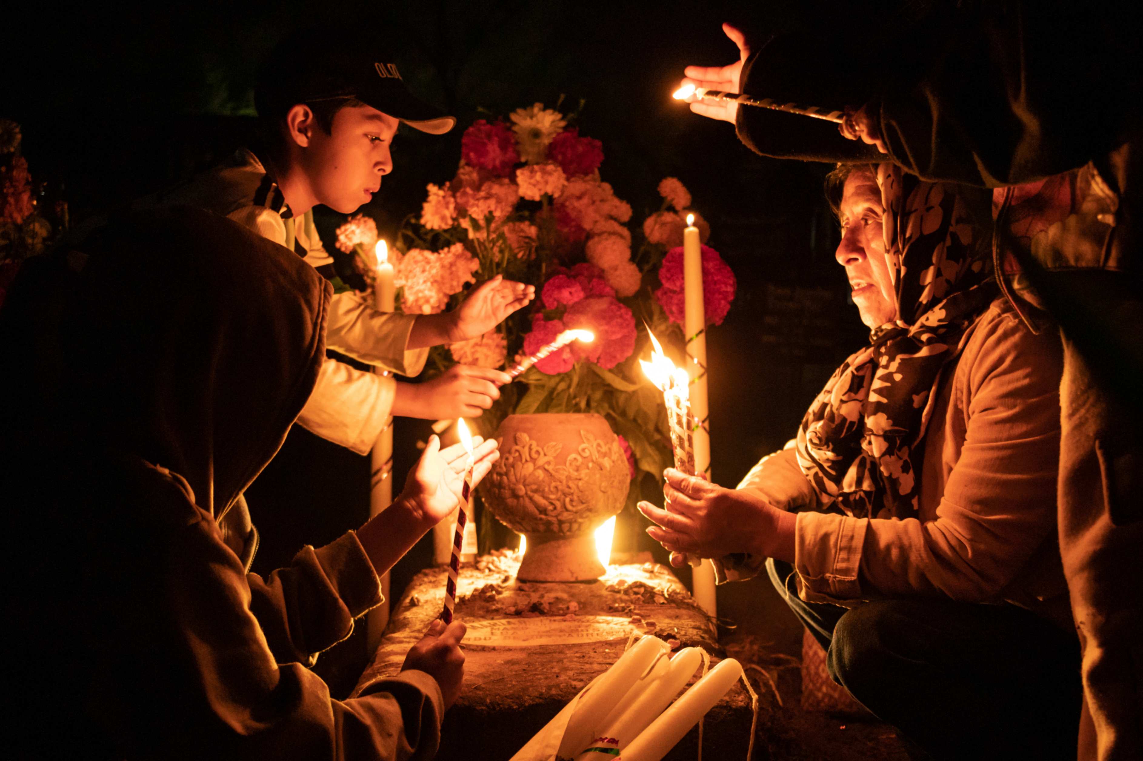 Unas personas sostienen velas sobre una tumba decorada con flores en un cementerio de Atzompa, México, a última hora del martes 31 de octubre de 2023. En una tradición que coincide con el Día de Todos los Santos, el 1 de noviembre, y el Día de los Difuntos, el 2 de noviembre, las familias decoran las tumbas con flores y velas y pasan la noche en el cementerio, haciendo compañía a sus seres queridos fallecidos. (Foto: AP/María Alférez) Unas personas sostienen velas sobre una tumba decorada con flores en un cementerio de Atzompa, México, a última hora del martes 31 de octubre de 2023. En una tradición que coincide con el Día de Todos los Santos, el 1 de noviembre, y el Día de los Difuntos, el 2 de noviembre, las familias decoran las tumbas con flores y velas y pasan la noche en el cementerio, haciendo compañía a sus seres queridos fallecidos. (Foto: AP/María Alférez)