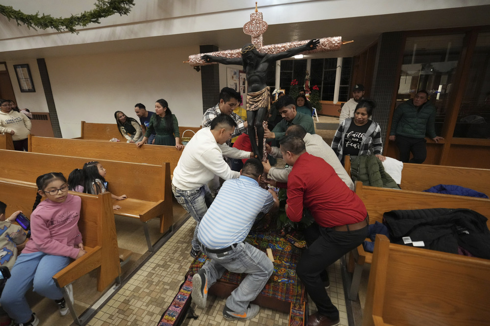 Guatemalan Black Christ of Esquipulas, St. Mary's Catholic Church, Worthington, Minn., Jan. 11, 2025. People in church surround large crucifix arranging it into place.