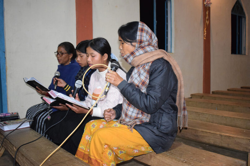 Catholic Khasi Senseful Dkhar, Mawlait village, Dec. 18, 2024. Dkhar, sits on bench in church singing into microphone.