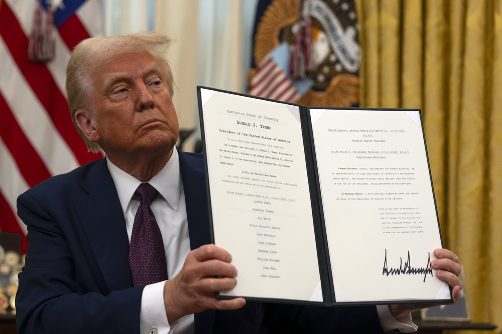 Trump signs clemency for abortion protesters in Oval Office, Washington, D.C., Jan. 23, 2025. Trump sits holding up document.
