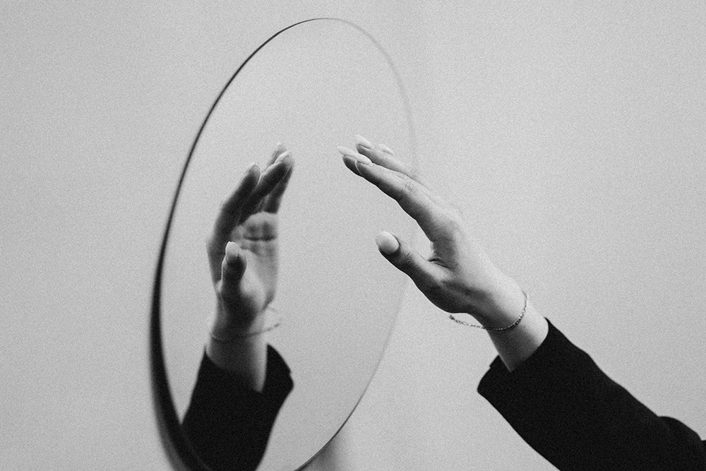 Un espejo con una mano reflejada (Foto: Unsplash/Sekatsky)