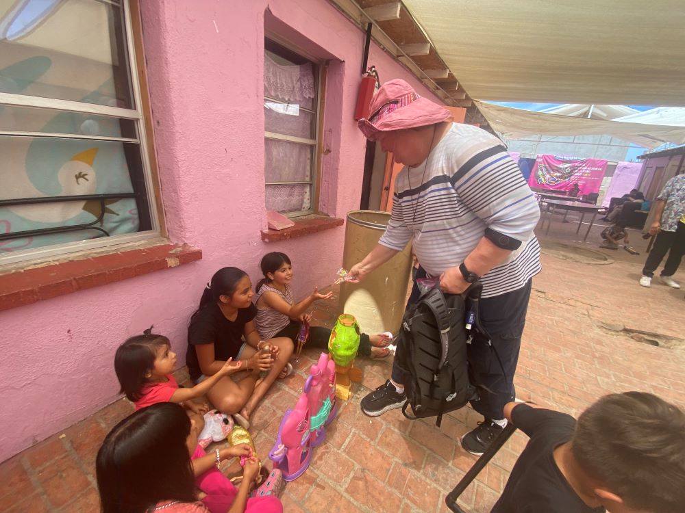 Sr. Lisa Buscher shares candy with children at a migrant shelter.