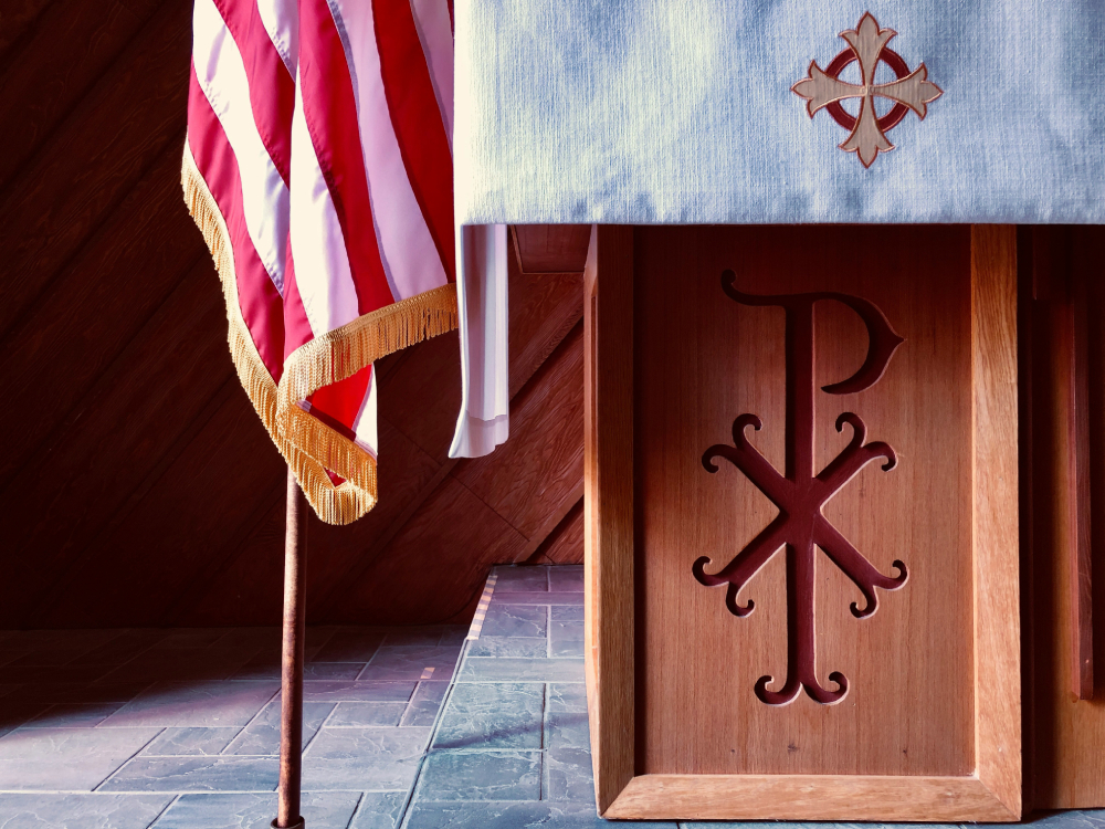 Brown wooden cross with flag of USA on top