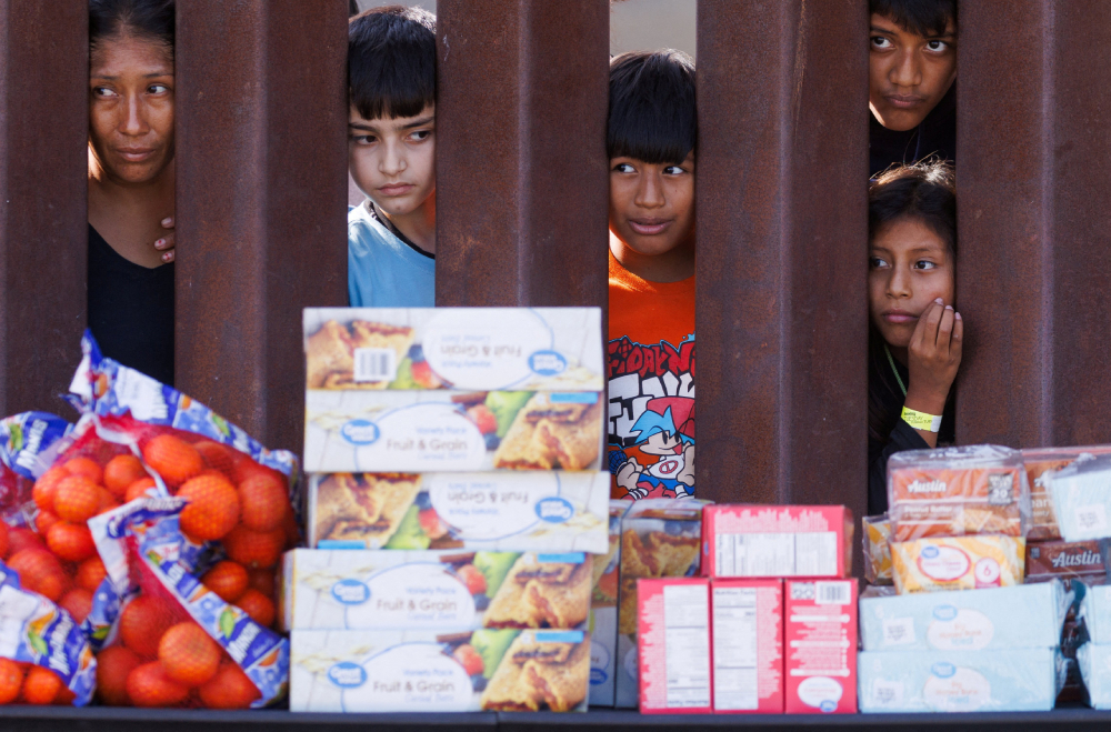 Migrants look through the border fence Migrants look through the border fence Sept. 12, 2023, toward food brought by aid workers after gathering between the primary and secondary border fences at the U.S.-Mexico border to wait for processing by U.S immigration officials in San Diego. (OSV News/Reuters/Mike Blake)