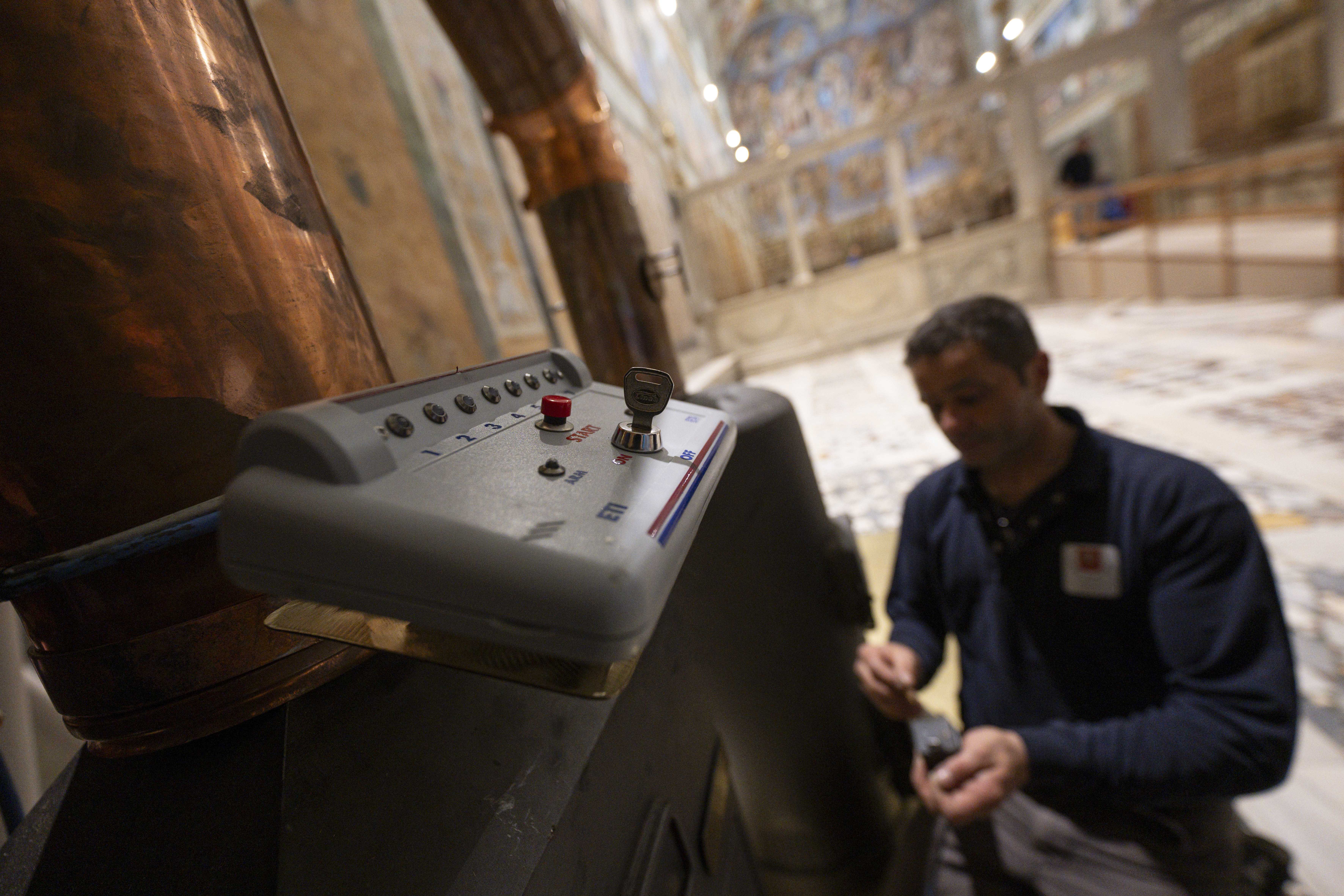 A worker May 2, 2025, inspects the machine that will add chemicals to produce dark black or clear white smoke when ballots are burned during the conclave to elect a new pope in the Sistine Chapel at the Vatican. Cardinals under the age of 80 will enter the conclave May 7. (CNS photo/Vatican Media)