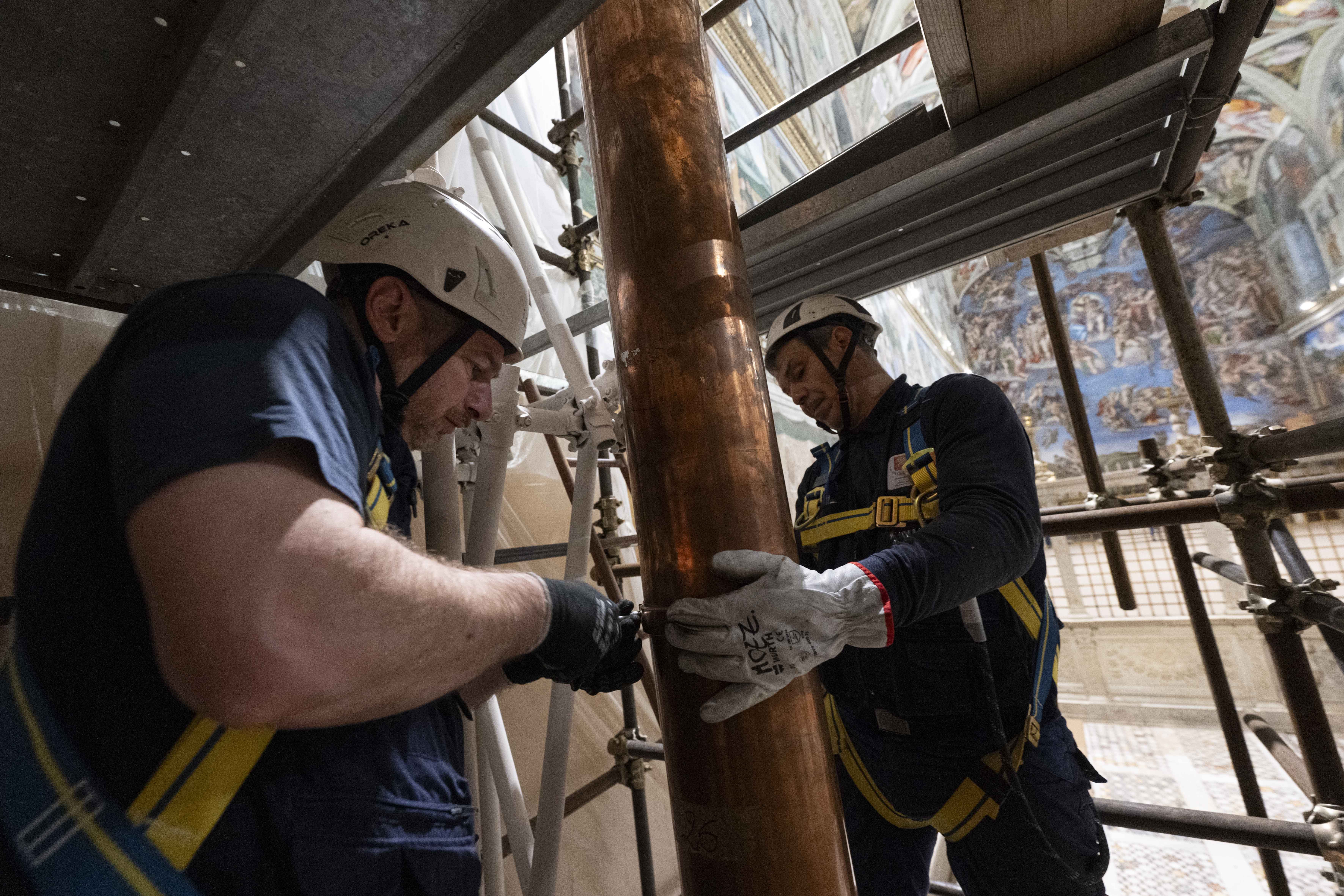 Workers on scaffolding May 2, 2025, attach the stove pipe to the stove that will be used to burn ballots during the conclave to elect a new pope in the Sistine Chapel at the Vatican. Cardinals under the age of 80 will enter the conclave May 7. (CNS photo/Vatican Media)