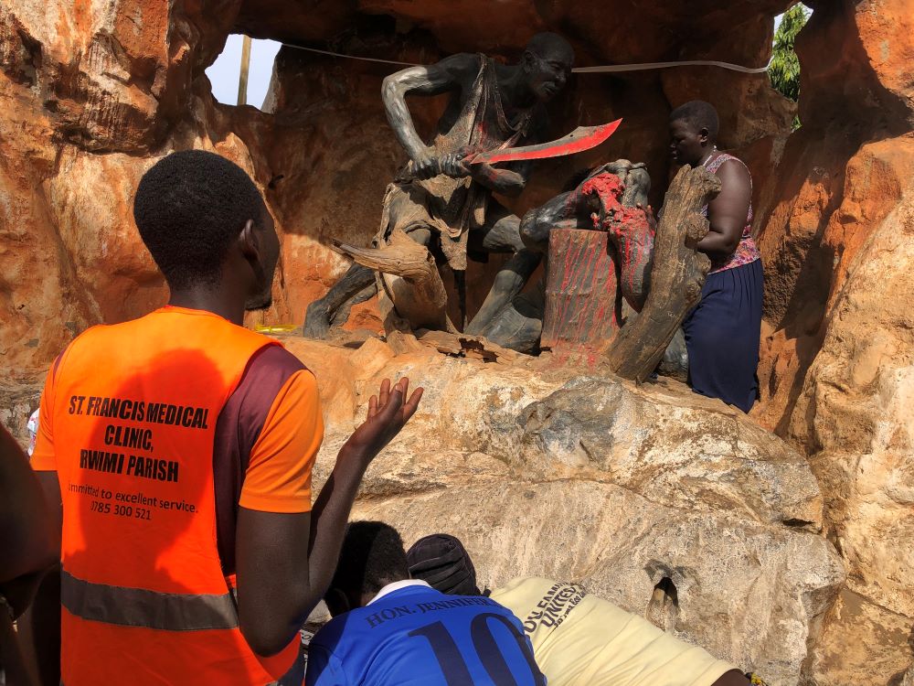 A pilgrim prays in front of a sculpture depicting the execution of a Uganda martyr. A pilgrim prays in front of a sculpture depicting the execution of a Uganda martyr.