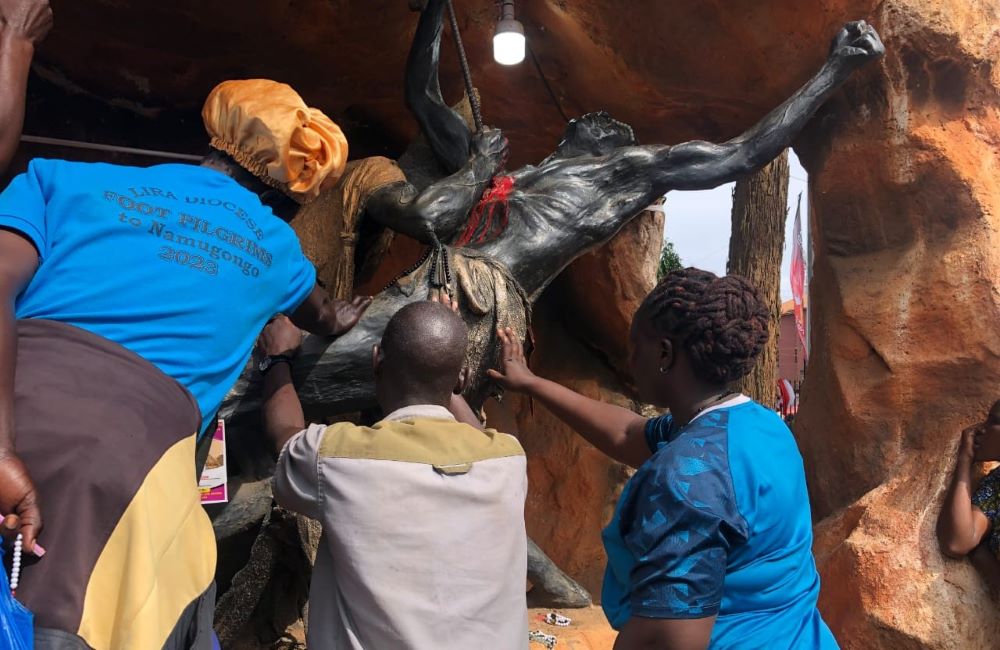 Pilgrims pray in front of a sculpture depicting the brutal execution of a Uganda martyr.  Pilgrims pray in front of a sculpture depicting the brutal execution of a Uganda martyr.