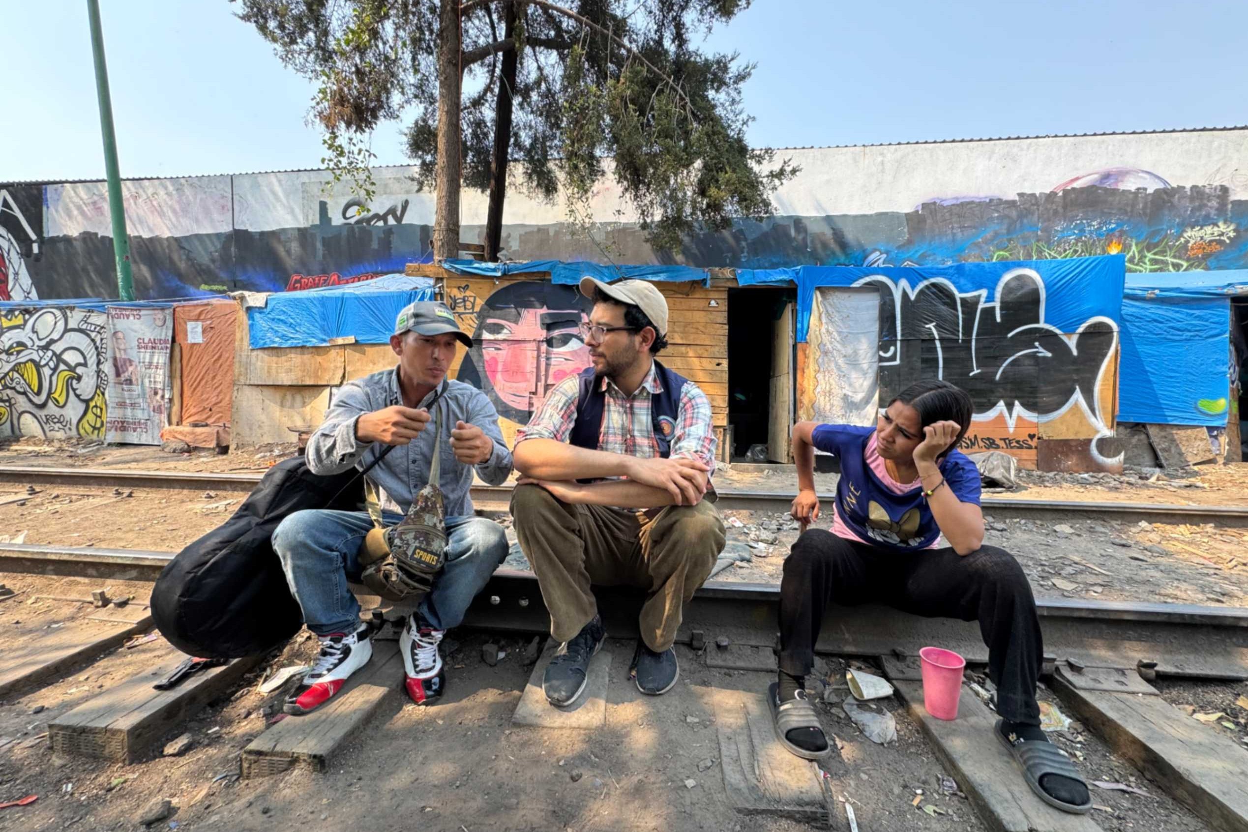Jesús Ricardo Rojas Romero, from Venezuela, speaks with Mario Monroy and Yesenia, also of Venezuela April 1, 2025 in a migrant camp in Mexico City. Monroy, outreach coordinator for CAFEMIN, a shelter for women and families, says that in his work he sees the cruelest side of humanity in the treatment of migrants. (GSR photo/Rhina Guidos)