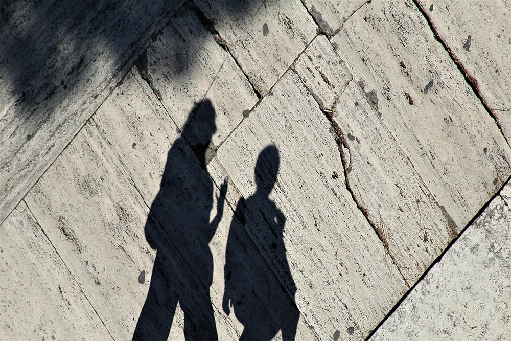 Shadows of two people walking along a street (Unsplash/Anne Nygard)