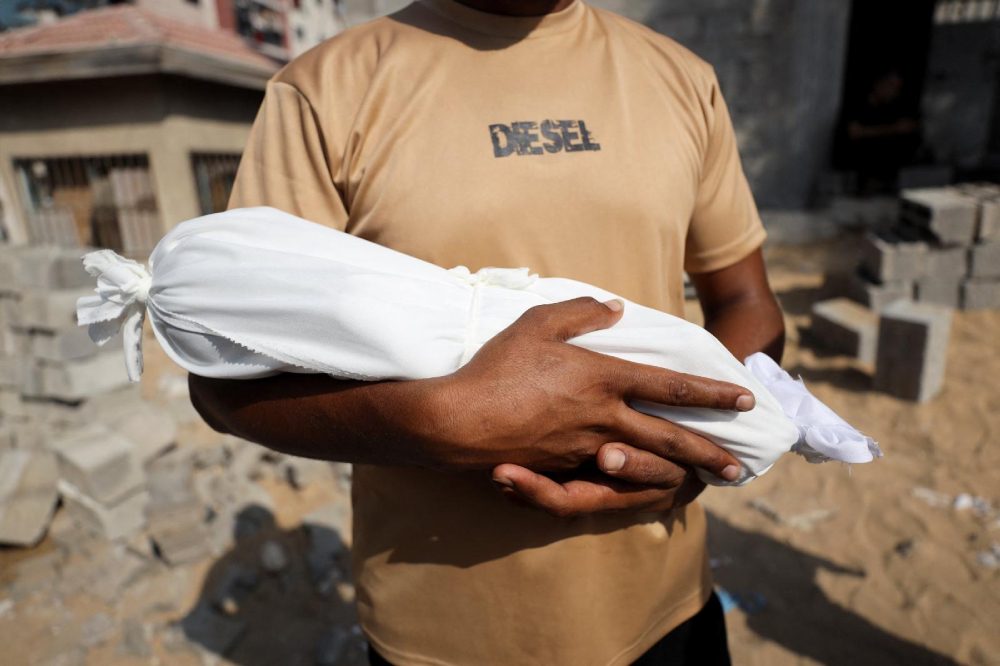 Adham carries the body of his nephew who died of starvation Adham carries the body of his nephew, 6-week-old Yousef al-Safadi, who died of starvation, according to health officials, in Gaza City July 22, 2025. For months, U.N. officials, aid groups and experts have warned that Palestinians in the Gaza Strip are on the brink of famine without formally declaring one. (OSV News/Khamis Al-Rifi/Reuters)
