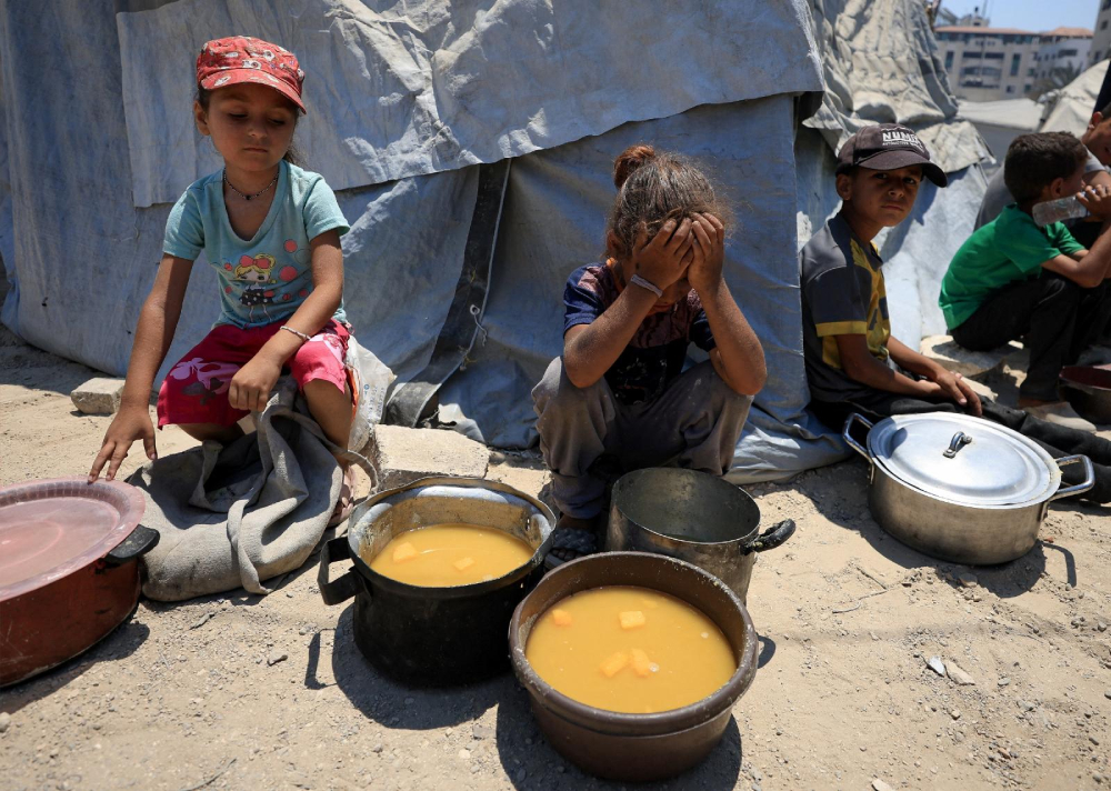 Palestinian children react near pots of food from a charity kitchen in Gaza Palestinian children react near pots of food from a charity kitchen in Gaza City July 25, 2025, amid a hunger crisis. For months, U.N. officials, aid groups and experts have warned that Palestinians in the Gaza Strip are on the brink of famine without formally declaring one. (OSV News/Dawoud Abu Alkas/Reuters)