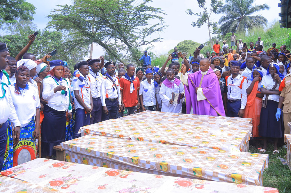 Fr. Aime Lokana Dhego sprinkles holy water on caskets during a funeral Mass in Komanda, in Congo's province of Ituri, July 28, for victims of a horrific attack on the Catholic church in Komanda. At least 40 faithful were shot or killed with machetes during an overnight vigil in the church July 27. (OSV News/Courtesy of Fr. Justin Zanamuzi)